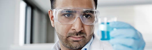 Lab technician holding a beaker with liquid