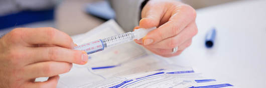 Person removing a cap from a syringe