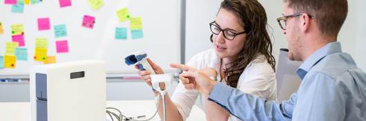 Two people in a conference room testing medical equipment