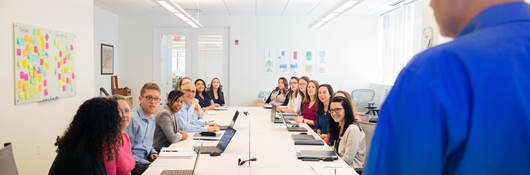 Person presenting to a conference room full of people