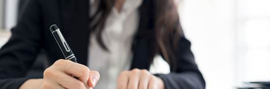 Person signing paperwork in an office 