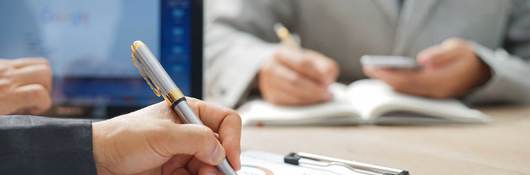 Close up of a person making notes on a printed out report on a clipboard