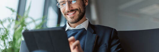 Business professional sitting on a couch while using a tablet