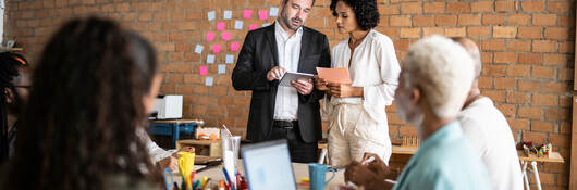 Business colleagues collaborating in front of a brick wall with post-it notes