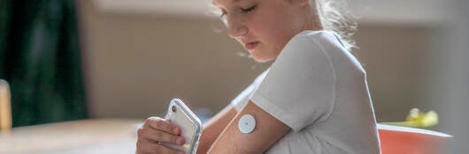 Girl monitoring medical device patch with smartphone