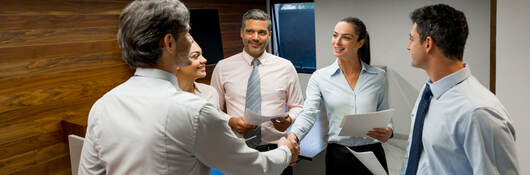 A group of business professionals greeting each other before a meeting