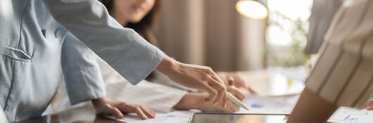 Group of business professionals having a discussion while looking at a tablet on a table
