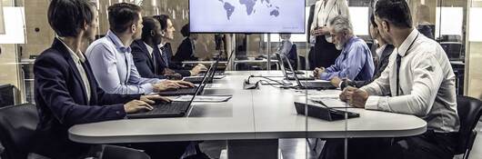 Group of business professionals having a meeting while looking at a map of the world