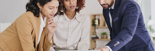 Three business colleagues reviewing content on a laptop