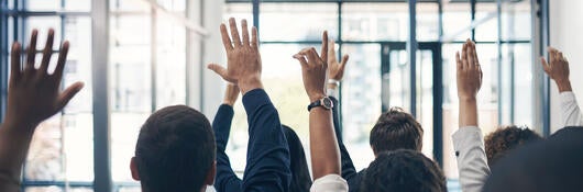 Group of people raising their hands to ask questions