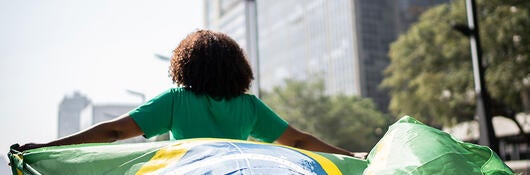 Person running through a city while holding the flag of Brazil