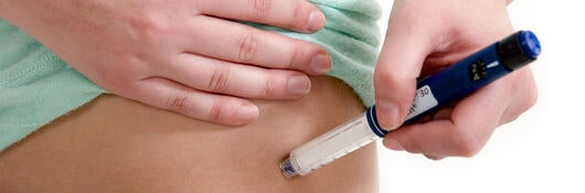 Person using an auto injector on their hip