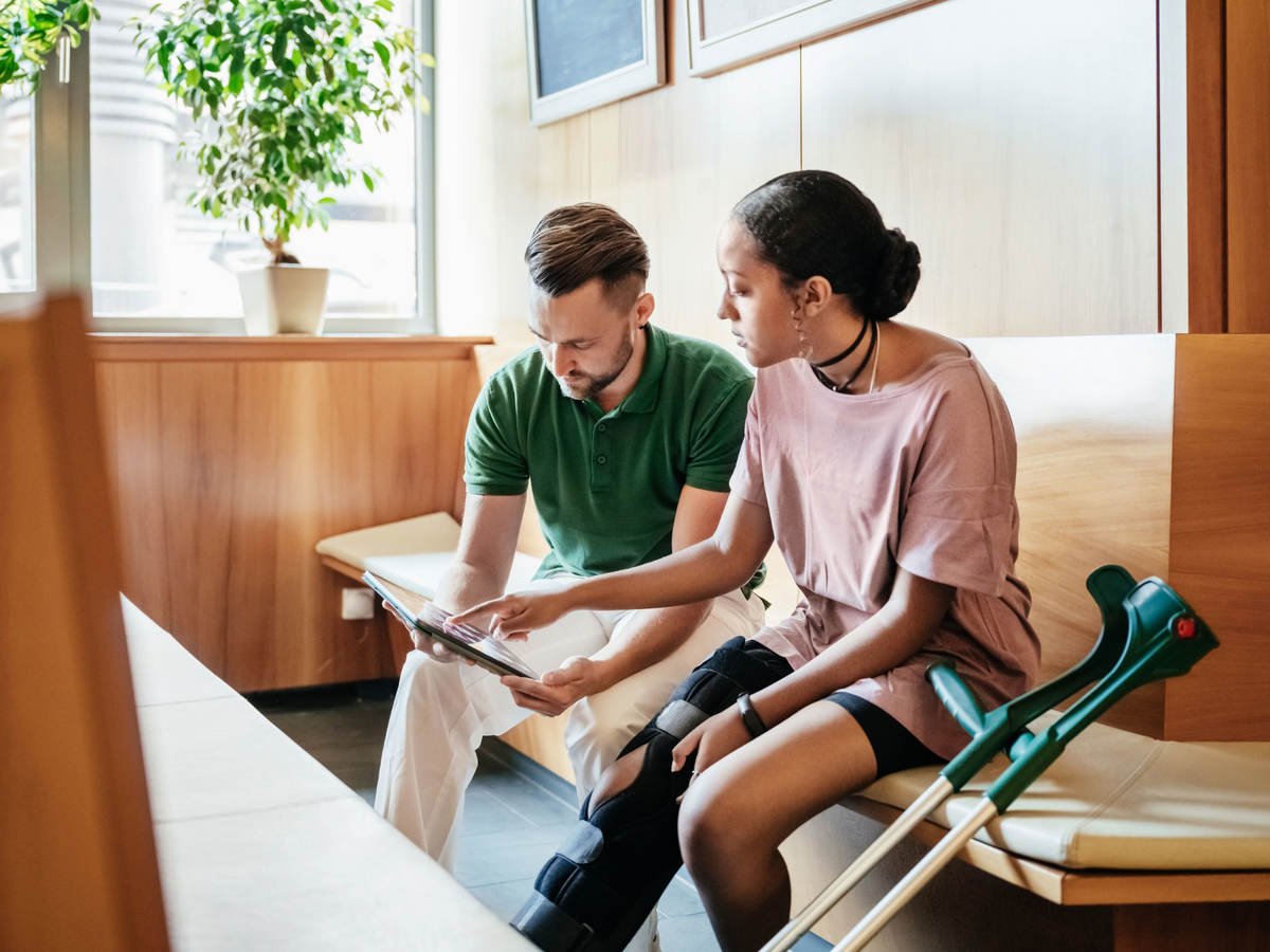 Person in leg brace looking over medical report with medical practitioner 