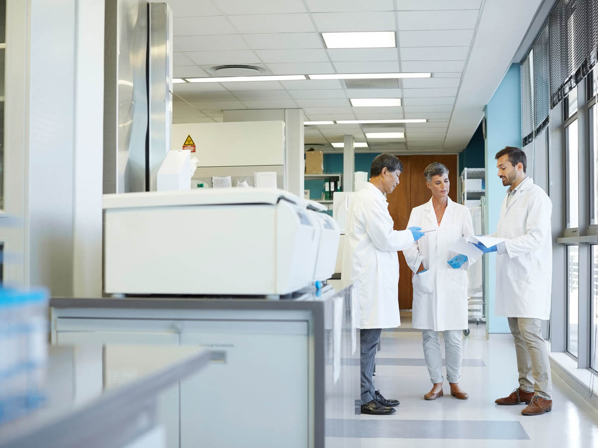 Group of lab technicians standing together looking at documents