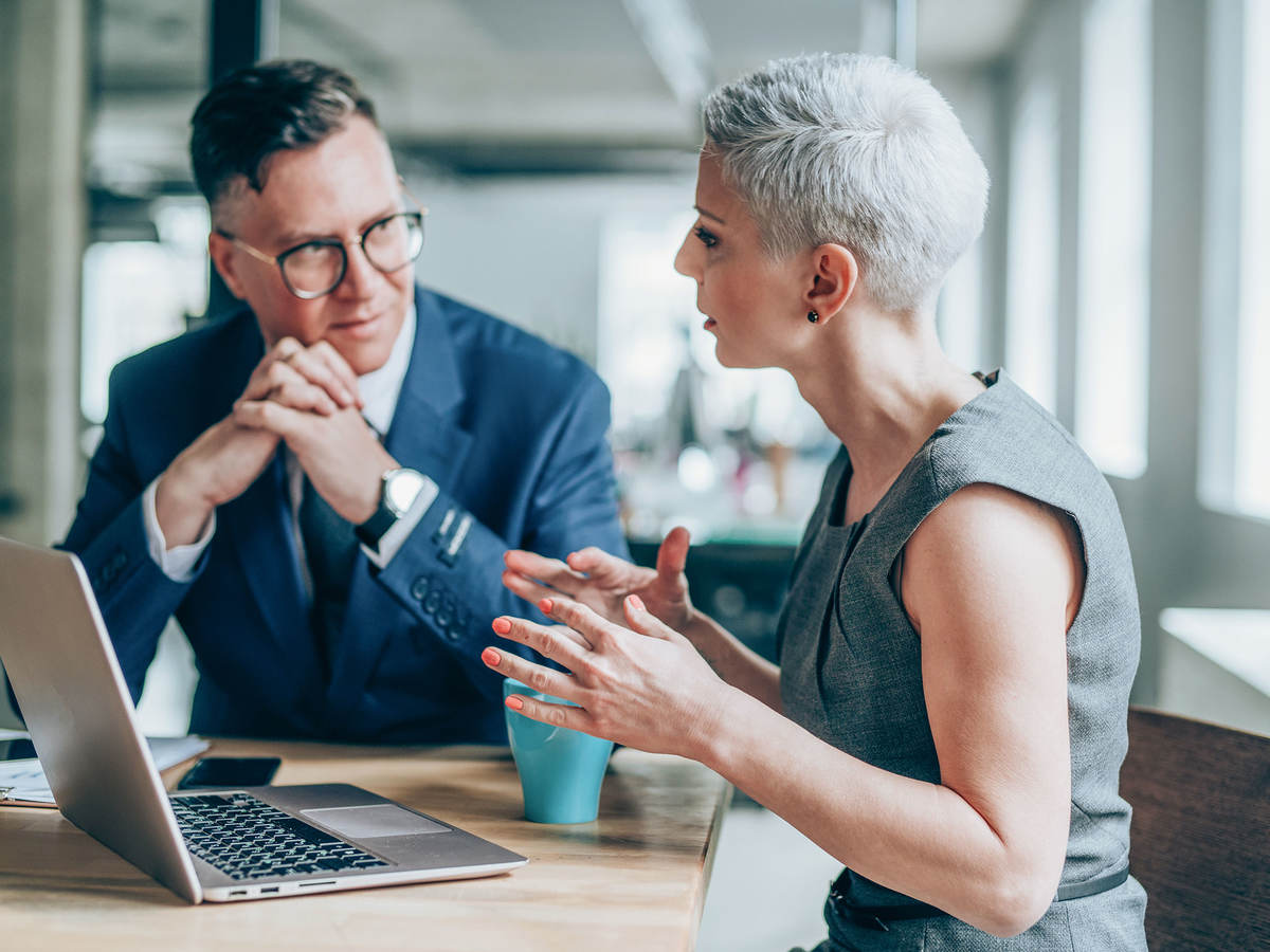 Two people having a discussion in front of a laptop 