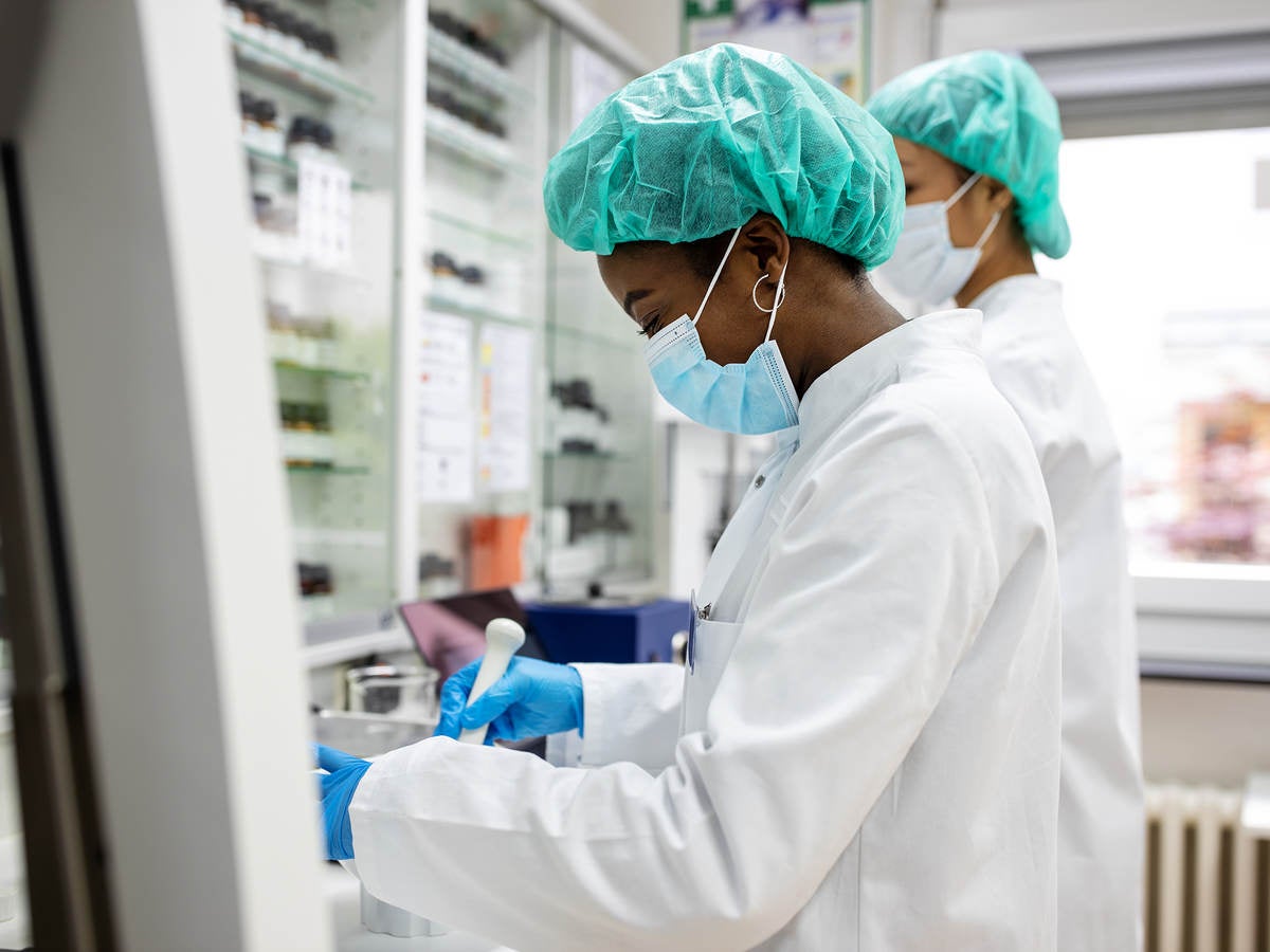 Two scientists making medicine at a laboratory. Doctors working together at pharmacy lab wearing protective work wear.