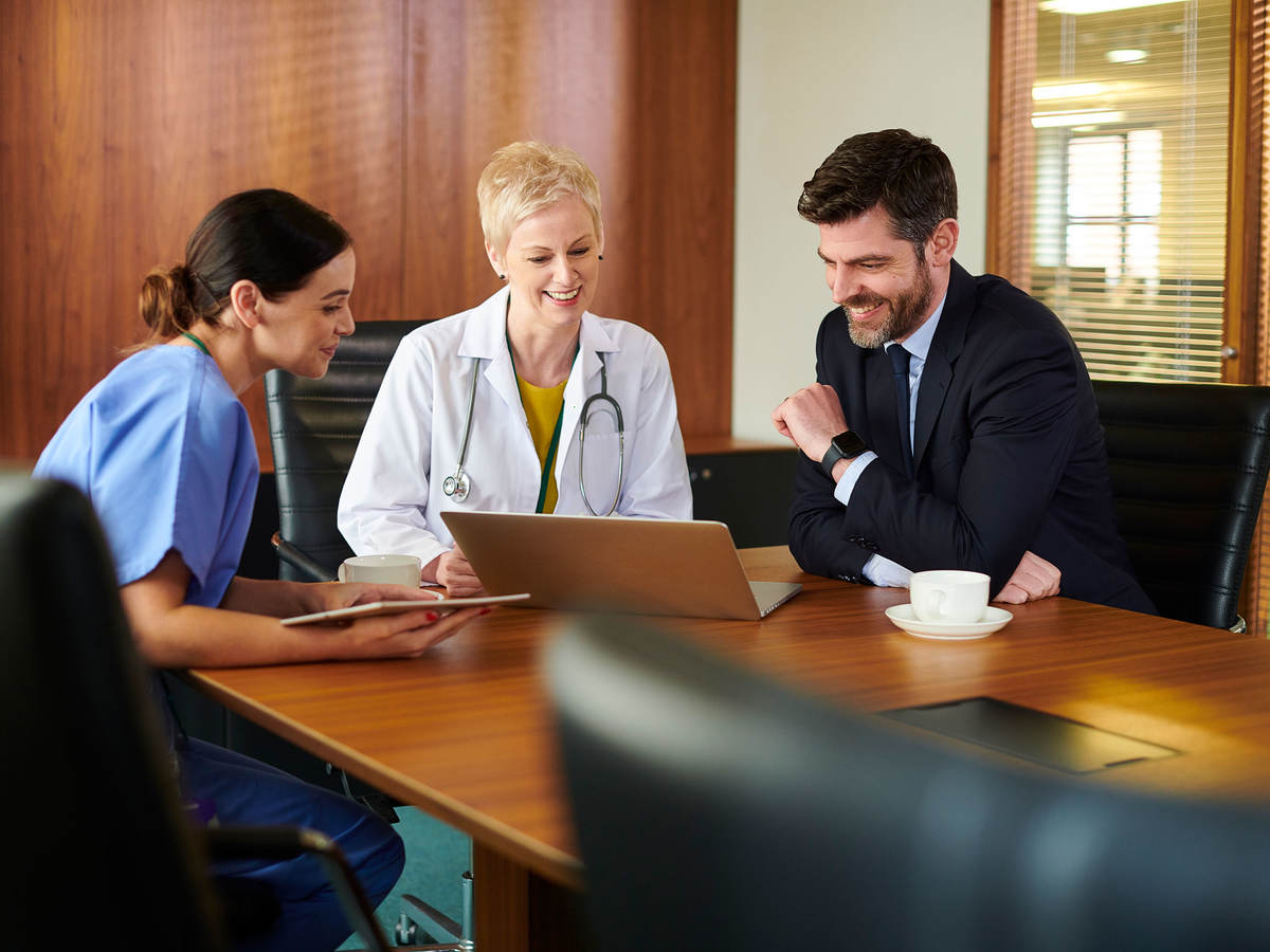 Business person sitting at a conference table with two medical professionals