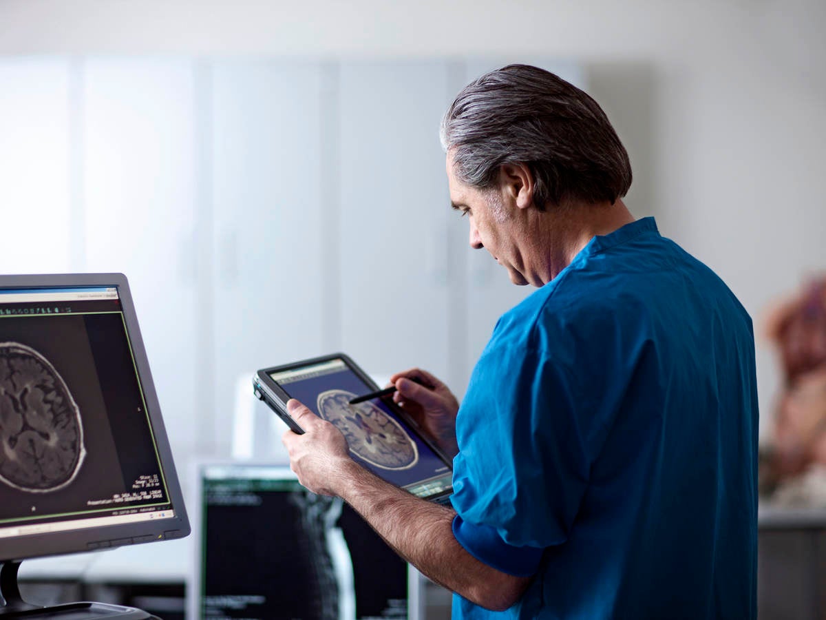 Doctor holding portable computer. Looking at MR scan image of human brain on screen