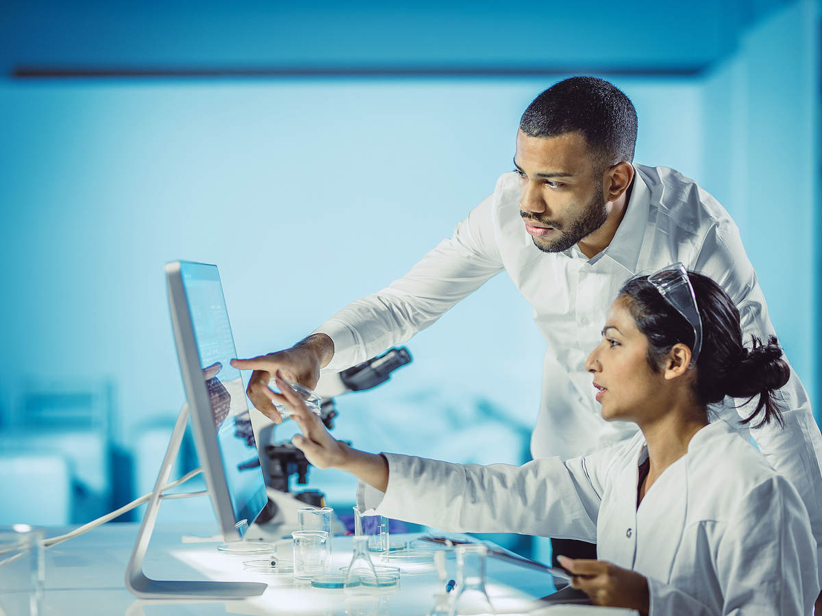 Two lab technicians pointing to data on a computer