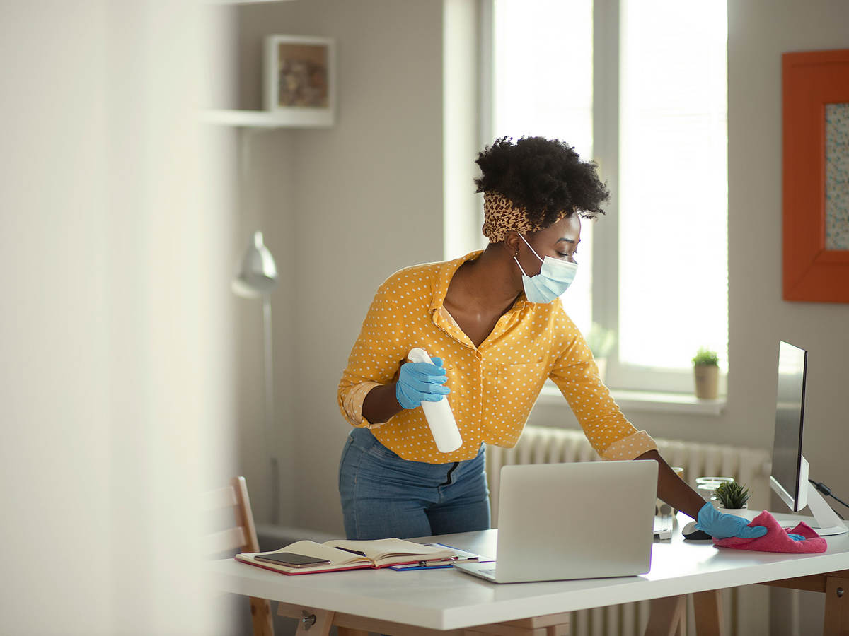 Person wearing a face mask and gloves cleaning a work desk