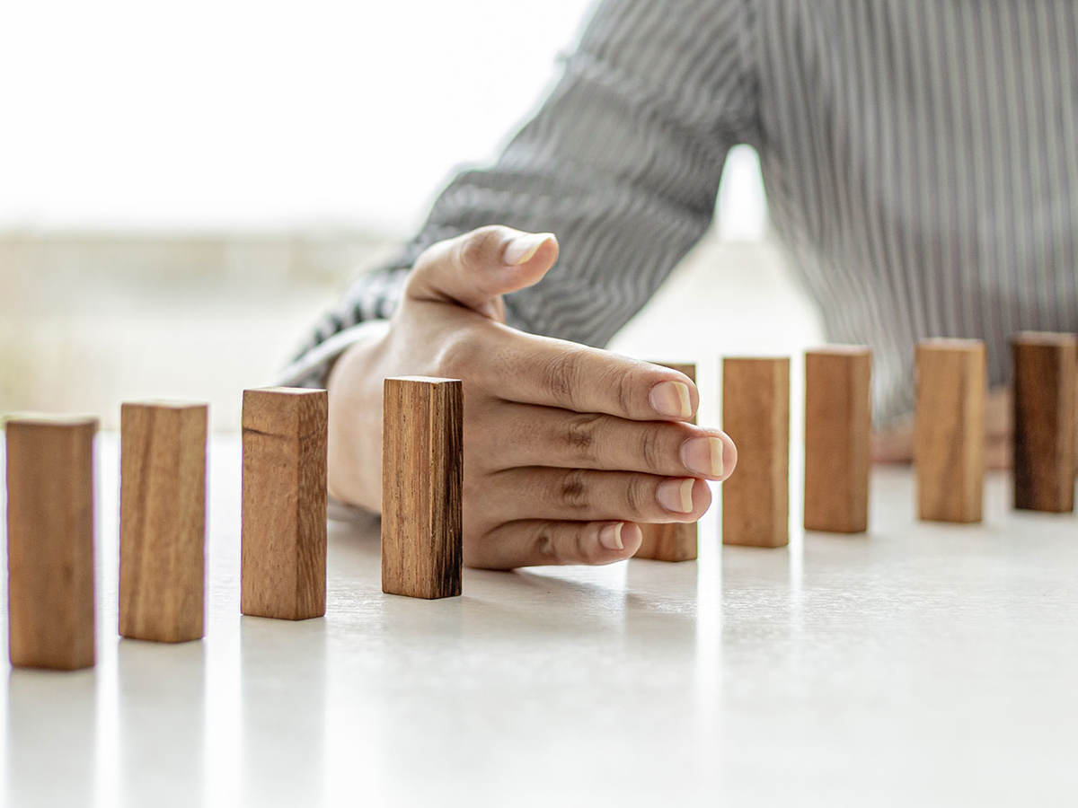 Dominos standing on a table with a hand in between two of the dominos