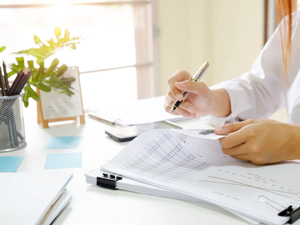Person sitting at desk reviewing documents with a pen