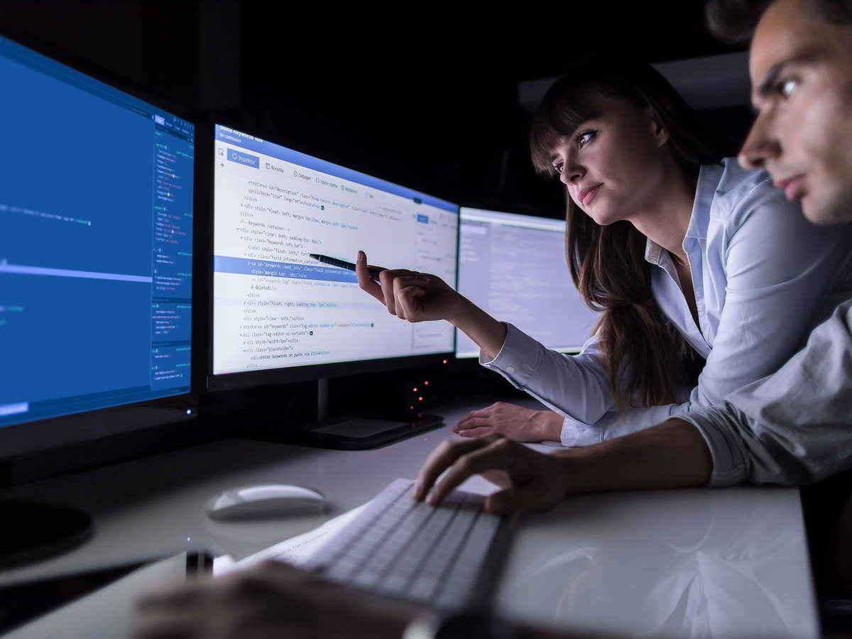 Two people in a dark office reviewing data on a computer