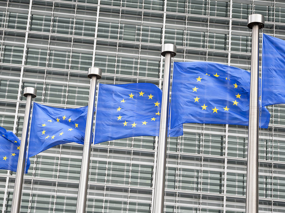 European union flags flying in front of a gray building