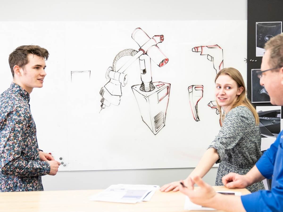 Three people reviewing drawings on a whiteboard