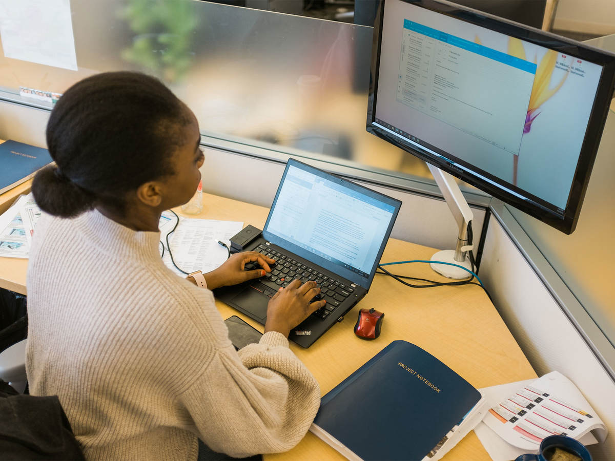 Person at a desk with laptop and monitor.