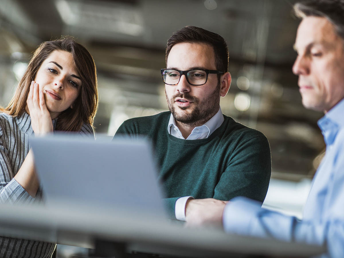 Three people looking at a laptop at work