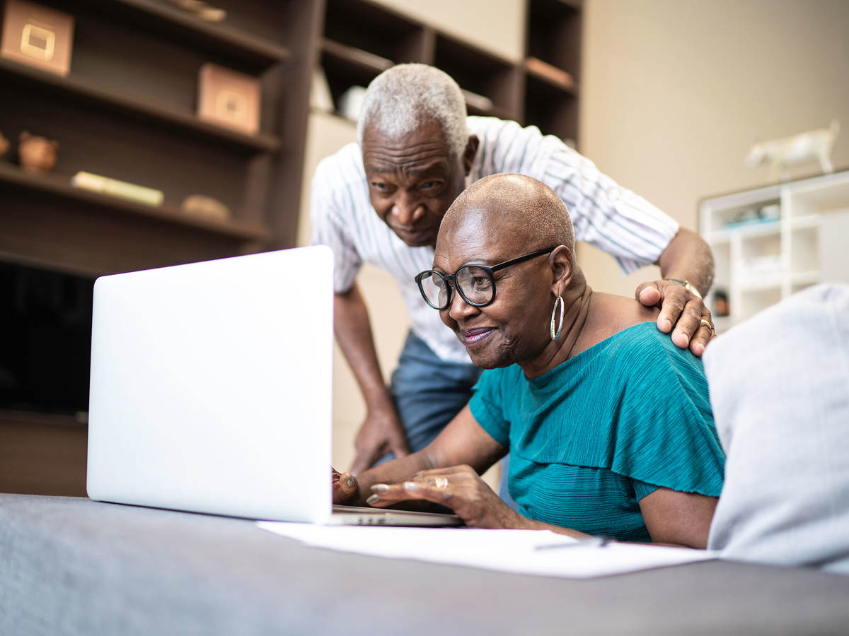 Two senior individuals looking at a laptop