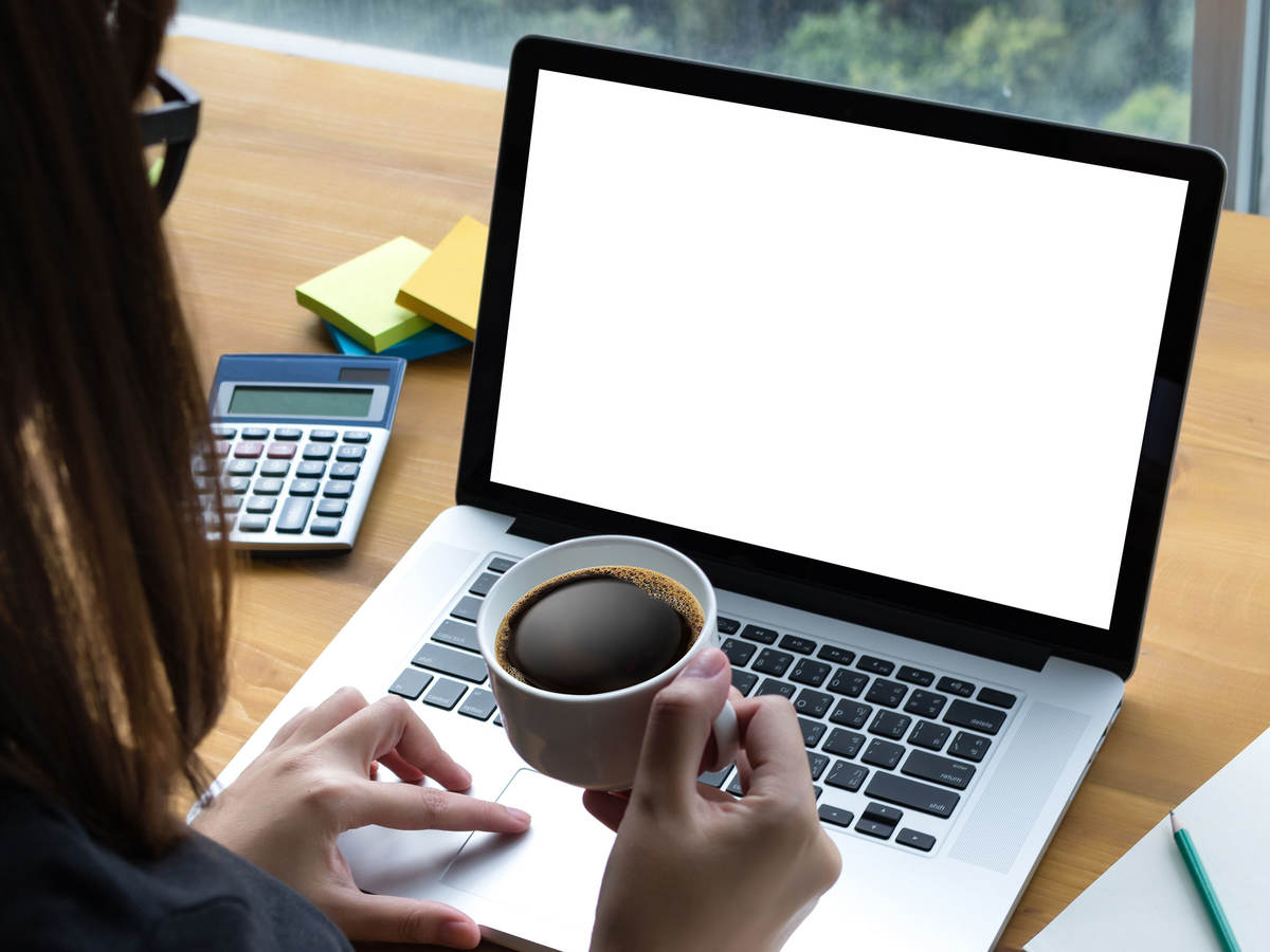 Person with coffee looking at a laptop