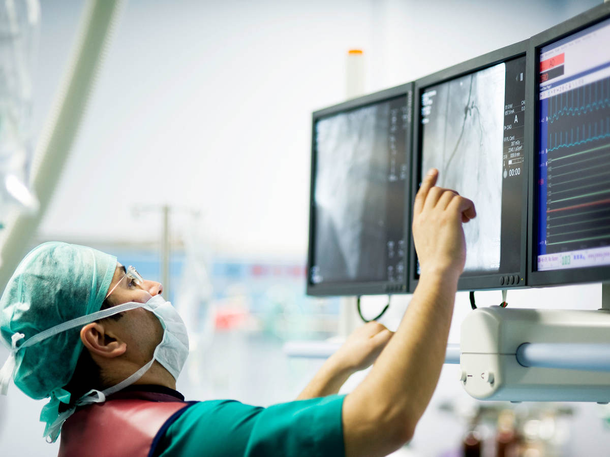 A surgeon is reviewing images on a computer screen