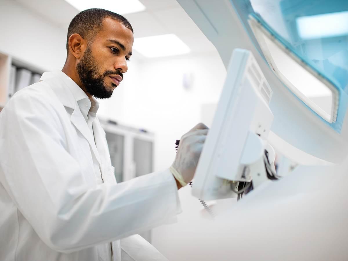 Scientist in lab coat working at the computer screen.