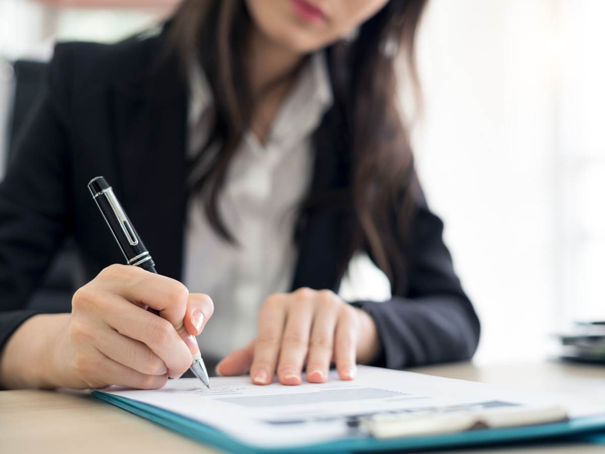 Person signing paperwork in an office 