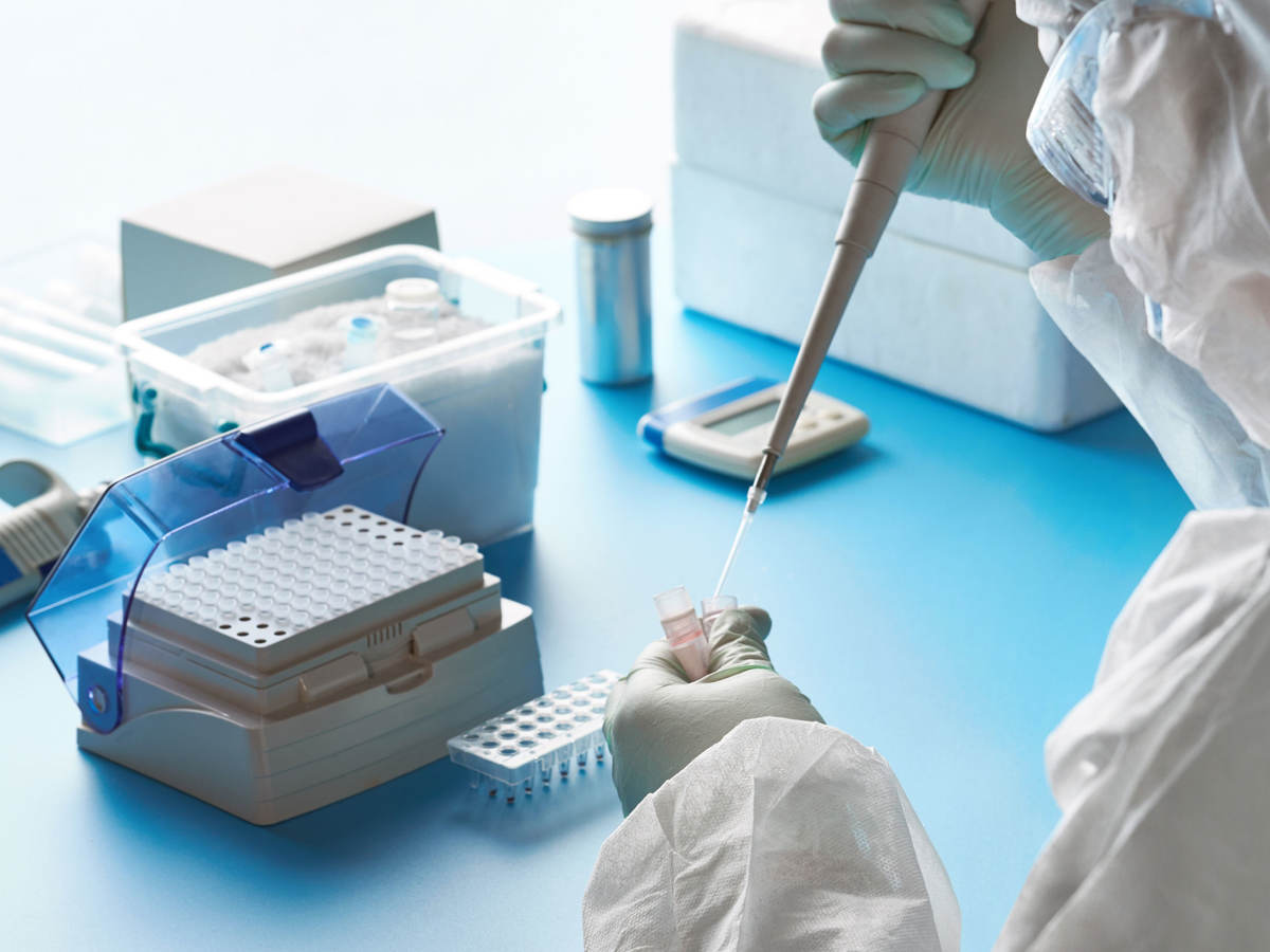 Epidemiologist in protective suit using a pipette