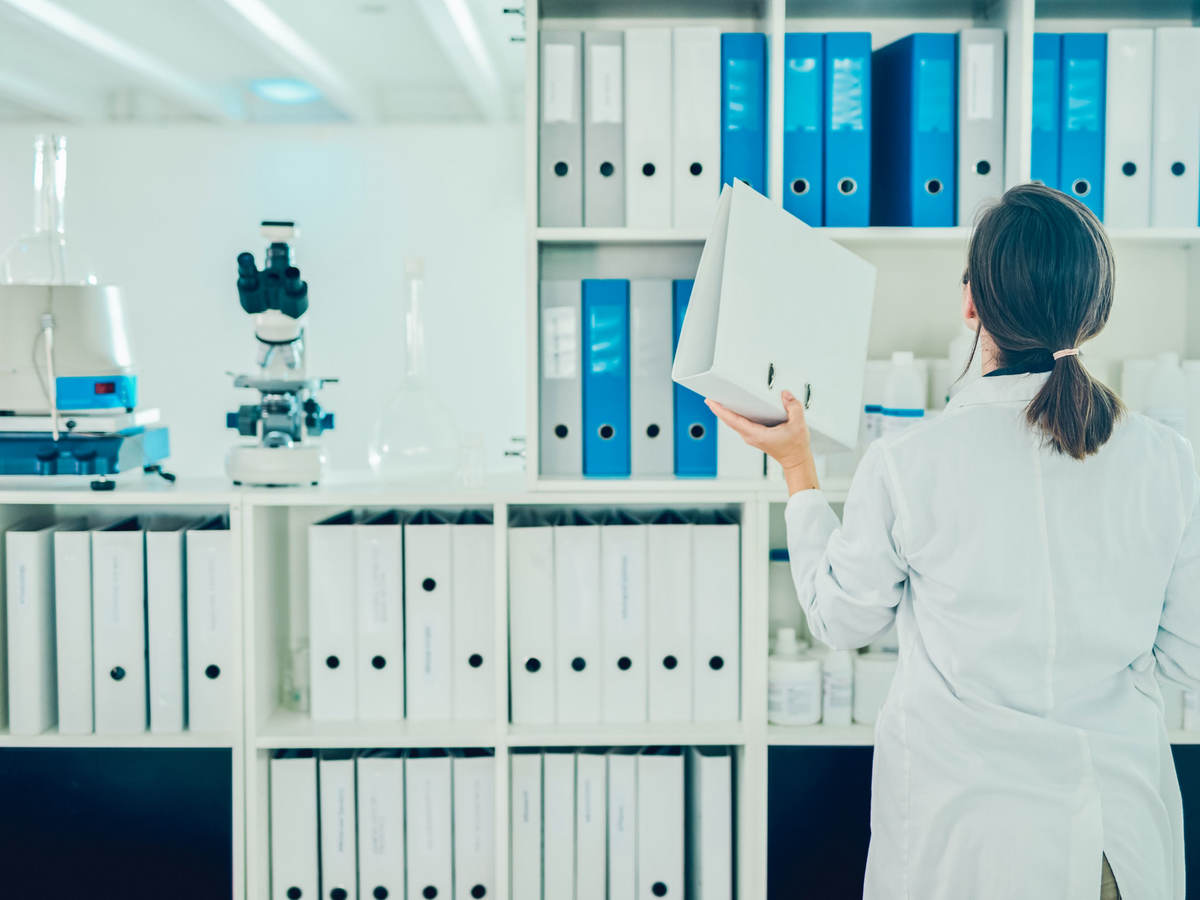 Lab tech putting away a binder on a shelf