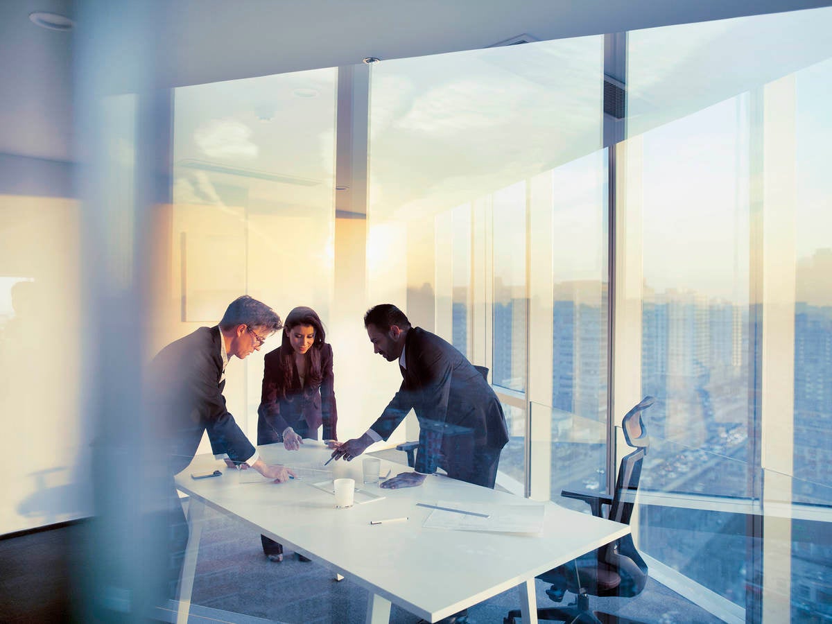 Business colleagues leaning over a table in an office while they work on their business strategy