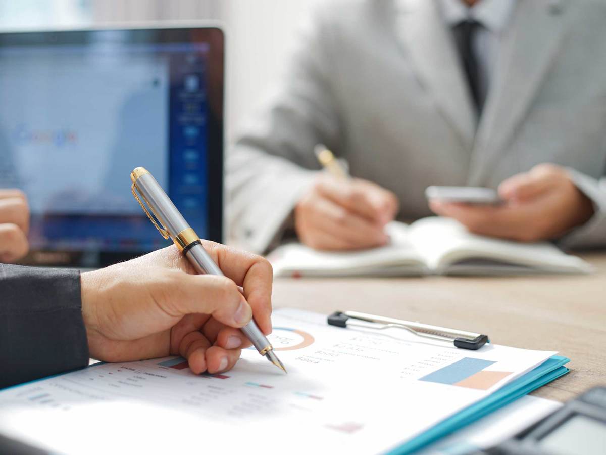 Close up of a person making notes on a printed out report on a clipboard