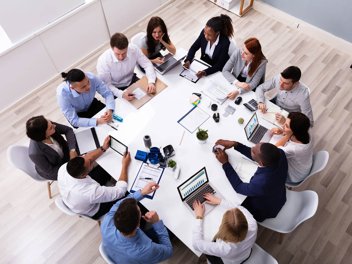 Overhead view of 12 people having a meeting at a square table