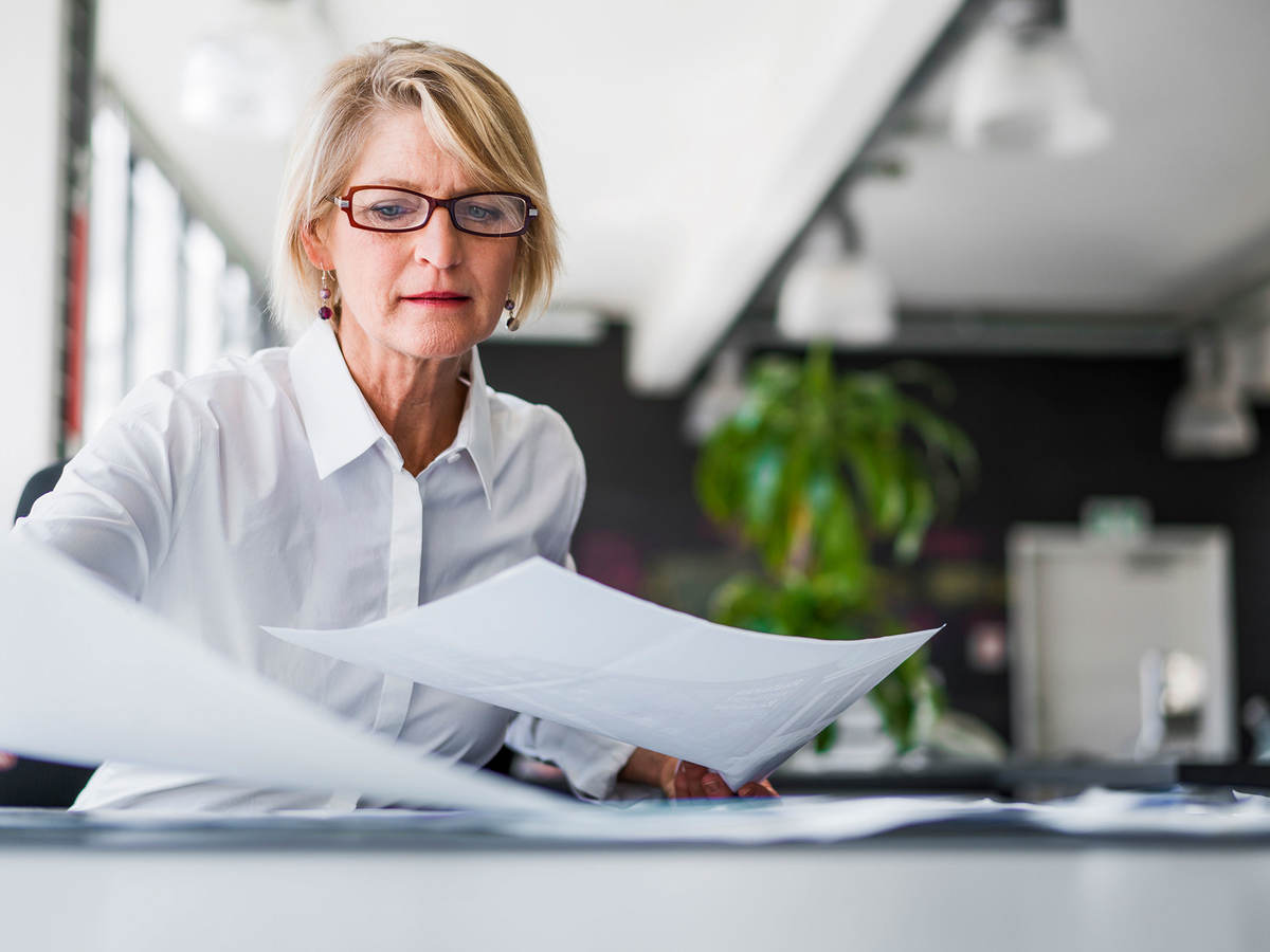 Manager reviewing reports by laying them out on a table