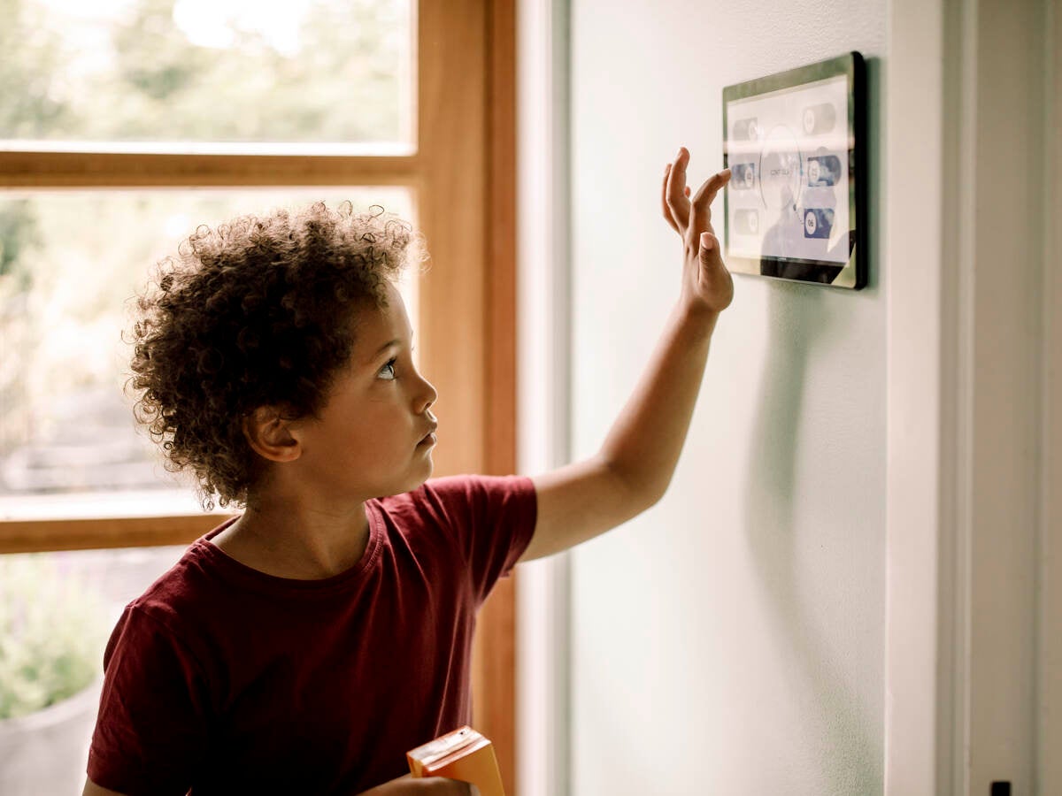 Boy checking smart thermostat.