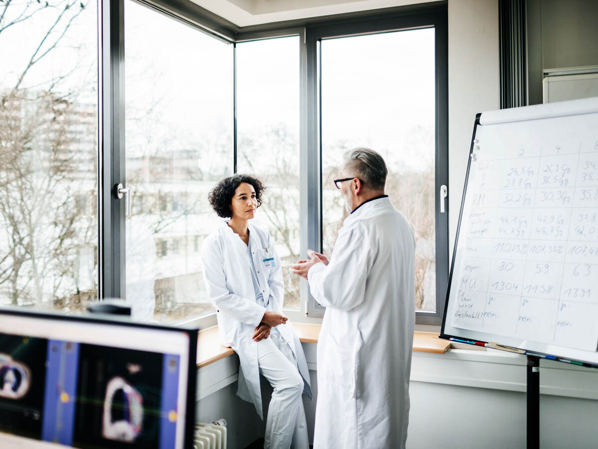 Two doctors talking next to a window in a doctor's office