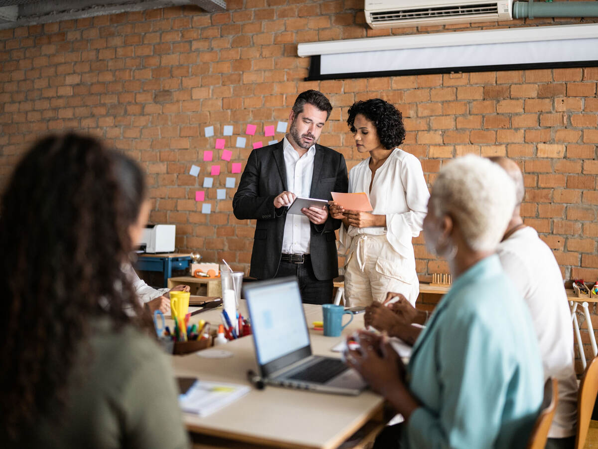 Business colleagues collaborating in front of a brick wall with post-it notes