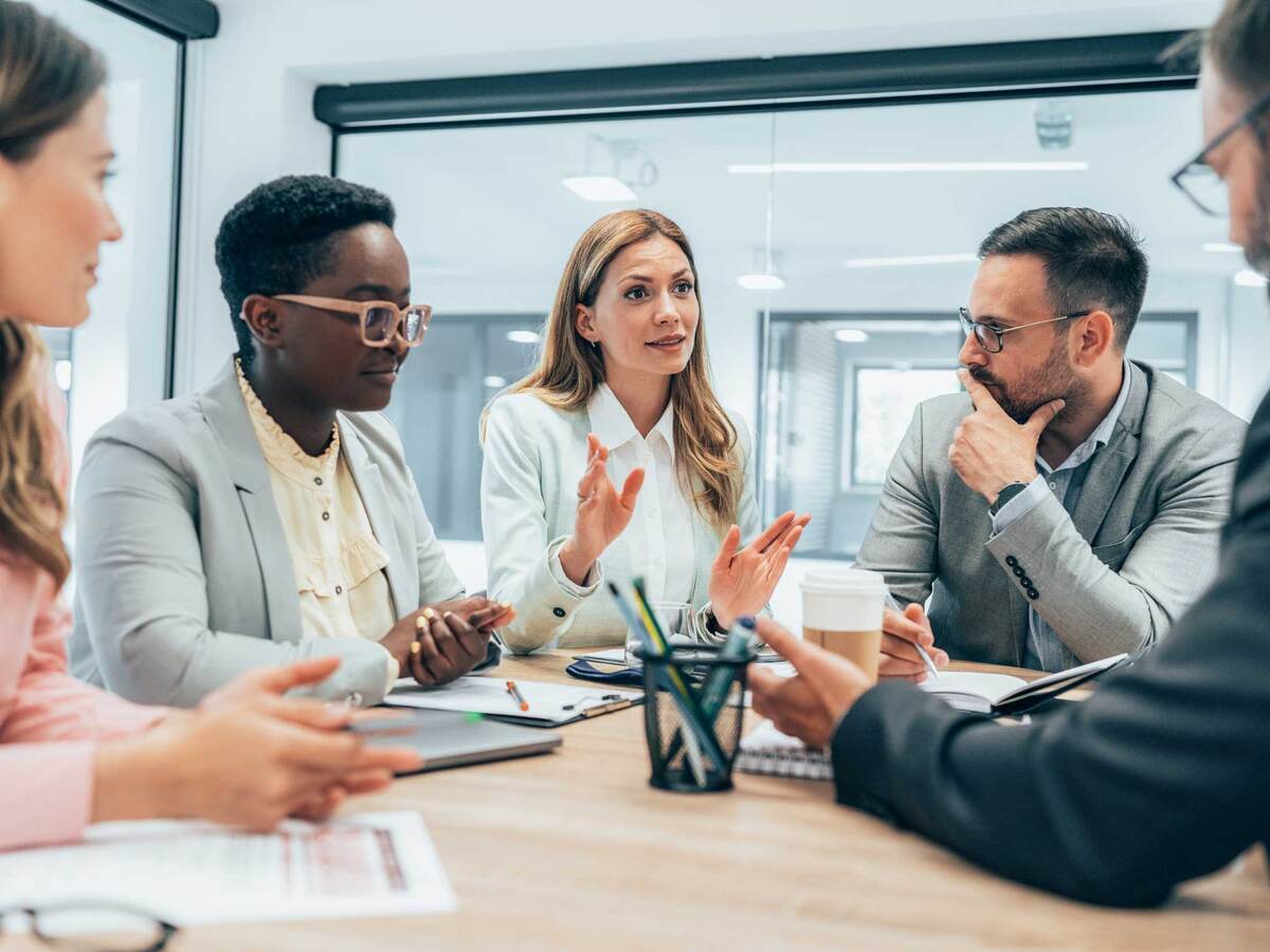 Five business colleagues discussing topics at a table