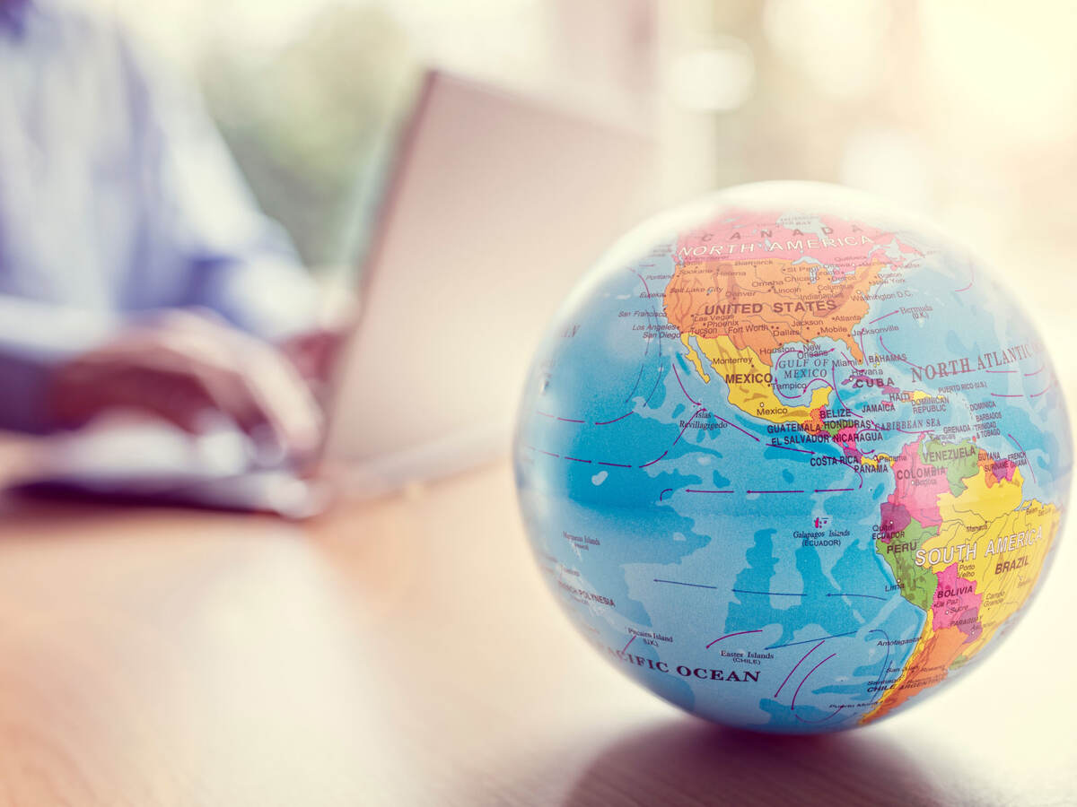 Close of a little globe with a person using a laptop in the background