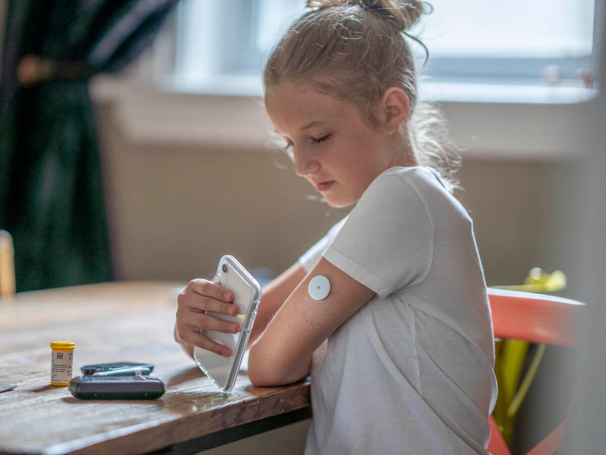 Girl monitoring medical device patch with smartphone