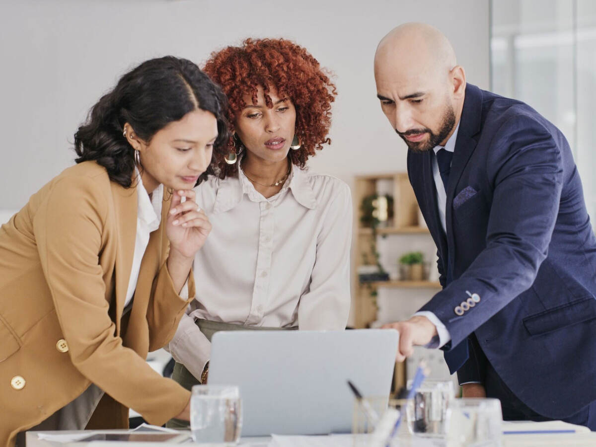 Three business colleagues reviewing content on a laptop