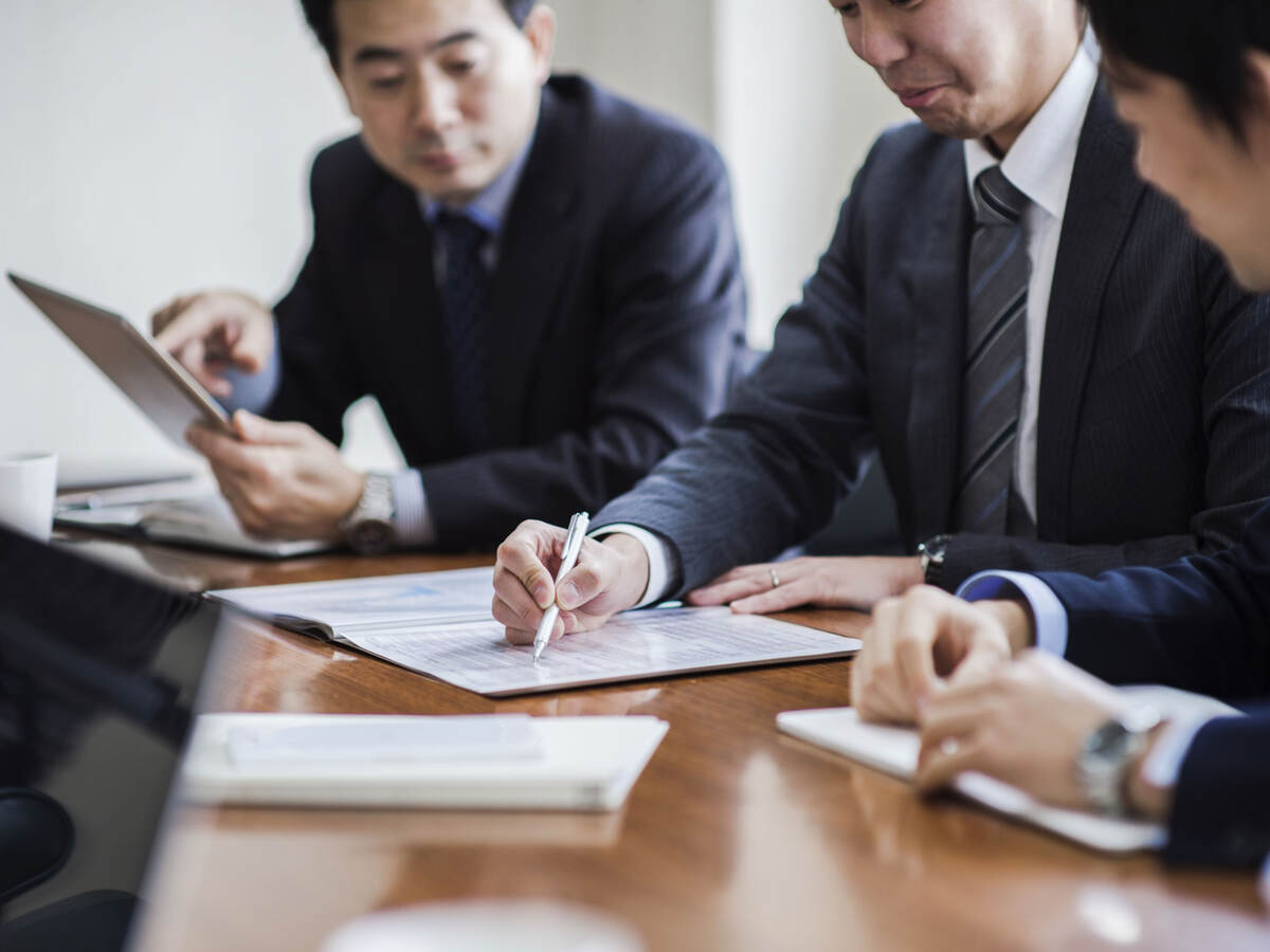 Three business professionals meeting to discuss market authorization of medical device regulations in Japan